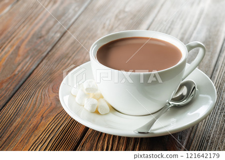 cocoa in white cup and marshmallows on saucer on table 121642179
