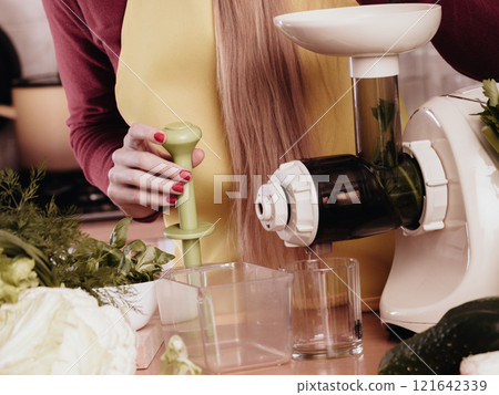Woman in kitchen making vegetable smoothie juice 121642339