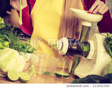 Woman in kitchen making vegetable smoothie juice 121642340