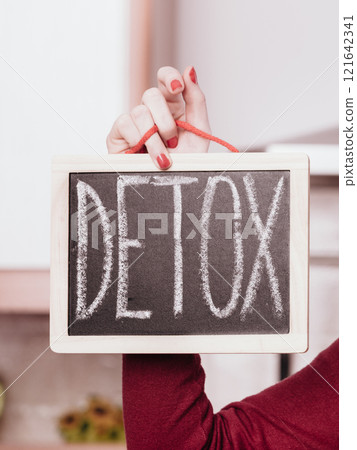 Happy woman holding board with detox sign 121642341