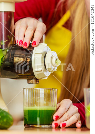 Woman in kitchen making vegetable smoothie juice Woman in kitchen making vegetable smoothie juice 121642342