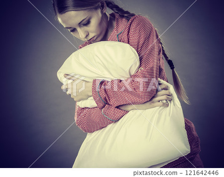Sad depressed girl in bed gripping pillow 121642446