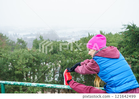 Woman wearing sportswear exercising outside during autumn Woman wearing sportswear exercising outside during autumn 121642499