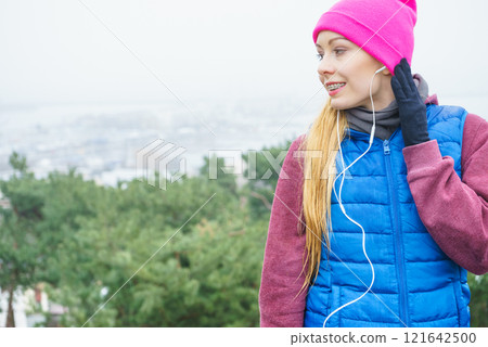 Woman wearing sportswear exercising outside during autumn 121642500