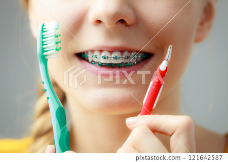 Girl with teeth braces using interdental and traditional brush 121642587