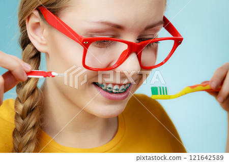 Girl with teeth braces using interdental and traditional brush 121642589