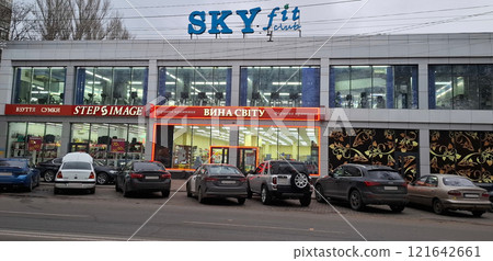 A two-storey building with shops and establishments. Along the road there are cars parked in front of a building with shops and a fitness center. A two-storey building with shops and establishments. Along the road there are cars parked in front of a building with shops and a fitness center. 121642661