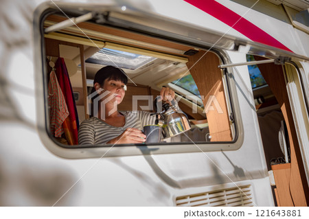 Woman cooking in camper, motorhome interior RV 121643881
