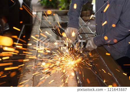 Heavy Industry Engineering Factory Interior with Industrial Worker Using Angle Grinder and Cutting a Metal Tube. 121643887
