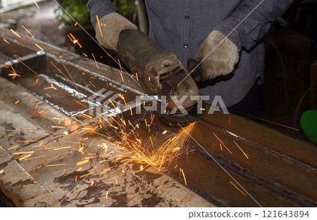 Heavy Industry Engineering Factory Interior with Industrial Worker Using Angle Grinder and Cutting a Metal Tube. 121643894