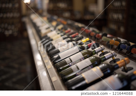 Row of wine bottles with dry red and white wine on wooden. Low depth of field. 121644088