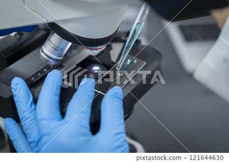 Experiment/research image: Researcher placing liquid on a glass slide 121644630