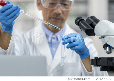 研究/實驗圖像：一位身穿白大褂的老人的手，用試管和滴管工作 121644809