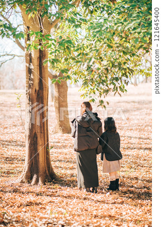 Mother and child standing under a tree in the park 121645400