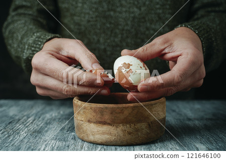 man peeling a brown hard-boiled egg 121646100