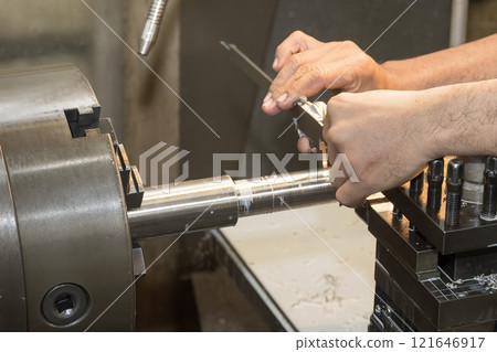 Close up scene the lath machine operator measuring dimension of turning parts by Vernier caliper. Close up scene the lath machine operator measuring dimension of turning parts by Vernier caliper. 121646917