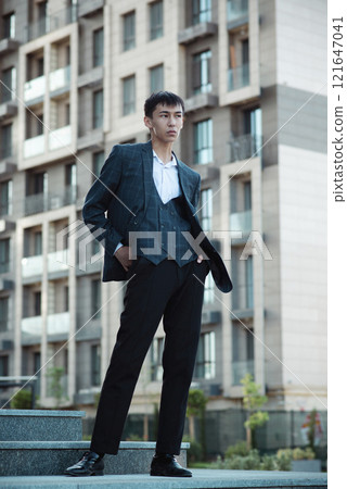 Oriental man in suit in downtown on building background Oriental man in suit in downtown on building background 121647041
