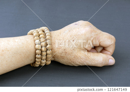 Wooden brown prayer beads bracelet worn on the wrists of elderly people. 121647149