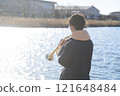 一個男孩在水邊吹小號 121648484