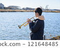 一個男孩在水邊吹小號 121648485