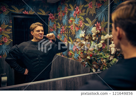 Man, superhero looking at mirror and brushing teeth, calm focus in vibrant surroundings, blending mundane with mindful relaxation. Man, superhero looking at mirror and brushing teeth, calm focus in vibrant surroundings, blending mundane with mindful relaxation. 121649856