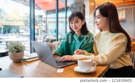 Two female college students studying in a stylish cafe. 121650605