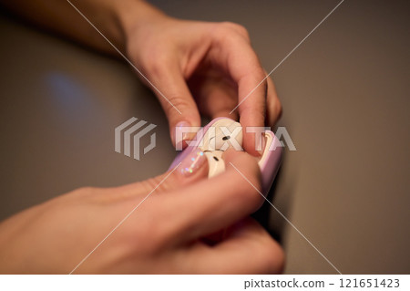 A Pair of Modern Wireless Earbuds Alongside Their Charging Case Being Held in Hands 121651423