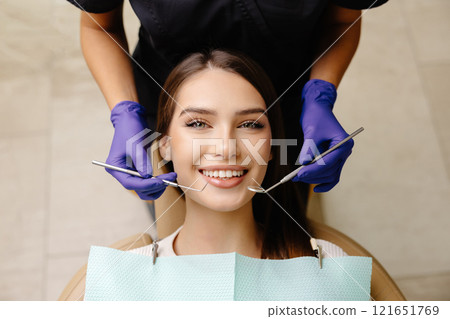 Happy patient during a visit to the dentist. The doctor is checking teeth using a dental instrument, ensuring proper oral care in the dentistry clinic 121651769