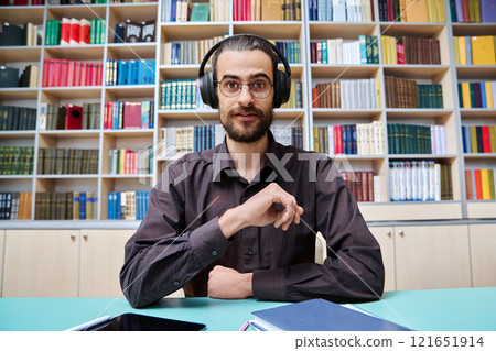 Webcam view young talking man making video call chat conference, in library Webcam view young talking man making video call chat conference, in library 121651914