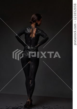 Anonymous woman painted in black in darkness 121652038