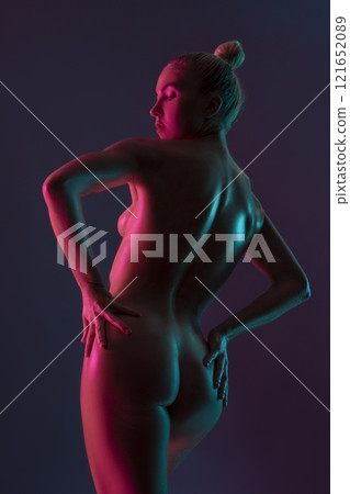 Naked sensual woman standing back with drawn hair on purple background in studio 121652089