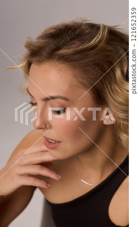 Confident Woman with Short Wavy Hair Wearing a Stylish Black Outfit in a Studio Setting Confident Woman with Short Wavy Hair Wearing a Stylish Black Outfit in a Studio Setting 121652359