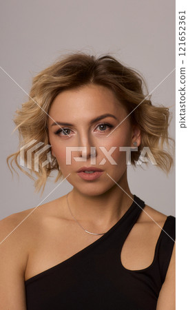 Confident Woman with Short Wavy Hair Wearing a Stylish Black Outfit in a Studio Setting Confident Woman with Short Wavy Hair Wearing a Stylish Black Outfit in a Studio Setting 121652361