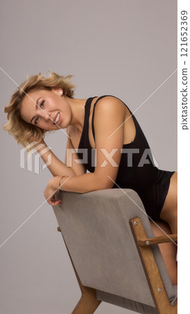 Confident Woman with Short Wavy Hair Wearing a Stylish Black Outfit in a Studio Setting Confident Woman with Short Wavy Hair Wearing a Stylish Black Outfit in a Studio Setting 121652369