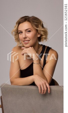 Confident Woman with Short Wavy Hair Wearing a Stylish Black Outfit in a Studio Setting Confident Woman with Short Wavy Hair Wearing a Stylish Black Outfit in a Studio Setting 121652381