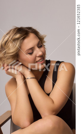 Confident Woman with Short Wavy Hair Wearing a Stylish Black Outfit in a Studio Setting Confident Woman with Short Wavy Hair Wearing a Stylish Black Outfit in a Studio Setting 121652385