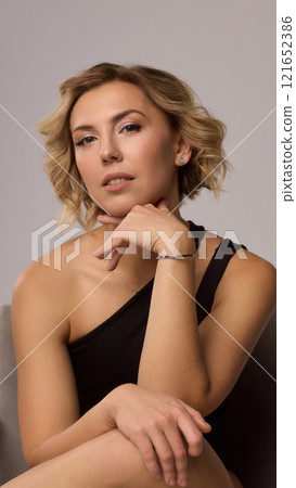 Confident Woman with Short Wavy Hair Wearing a Stylish Black Outfit in a Studio Setting Confident Woman with Short Wavy Hair Wearing a Stylish Black Outfit in a Studio Setting 121652386