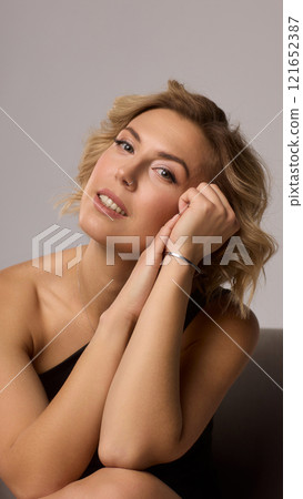 Confident Woman with Short Wavy Hair Wearing a Stylish Black Outfit in a Studio Setting Confident Woman with Short Wavy Hair Wearing a Stylish Black Outfit in a Studio Setting 121652387