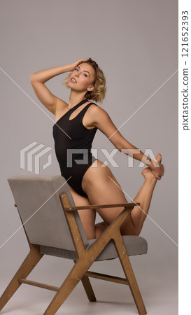 Confident Woman with Short Wavy Hair Wearing a Stylish Black Outfit in a Studio Setting 121652393