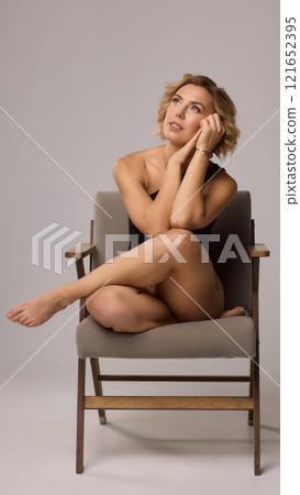 Confident Woman with Short Wavy Hair Wearing a Stylish Black Outfit in a Studio Setting 121652395