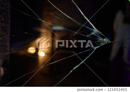Cracked Glass Window Featuring Distinct Impact Marks Evident on Its Surface and Structure 121652403