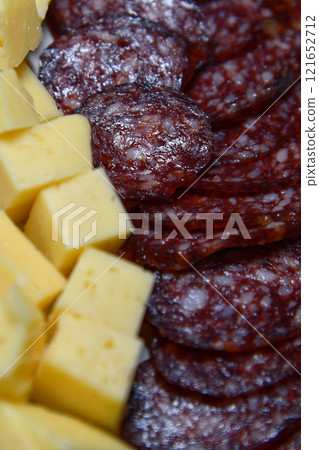 Sausage slices on wooden board with different snacks. Sausage slices on wooden board with different snacks. 121652712