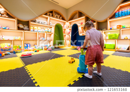 Child exploring a bright and organized indoor playroom with toys and activity stations Child exploring a bright and organized indoor playroom with toys and activity stations 121653168