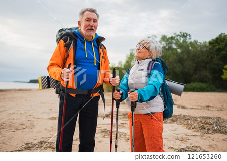 Hiking tourism adventure. Senior couple man woman enjoying outdoor recreation hiking on beach. Happy old people backpackers hikers enjoy walking hike trekking tourism active vacation beauty of nature Hiking tourism adventure. Senior couple man woman enjoying outdoor recreation hiking on beach. Happy old people backpackers hikers enjoy walking hike trekking tourism active vacation beauty of nature 121653260