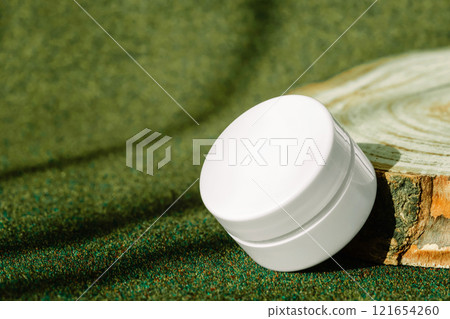 Jar of firming cream with collagen placed on round wooden display on green earthy toned background Jar of firming cream with collagen placed on round wooden display on green earthy toned background 121654260