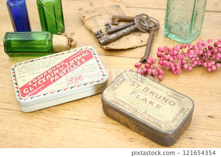 Antique tin cans, keys and bottles on a pine table Antique tin cans, keys and bottles on a pine table 121654354
