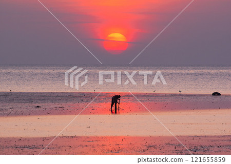 Silhouette of a fisherman against a calm sea during sunrise at Phuket city 121655859