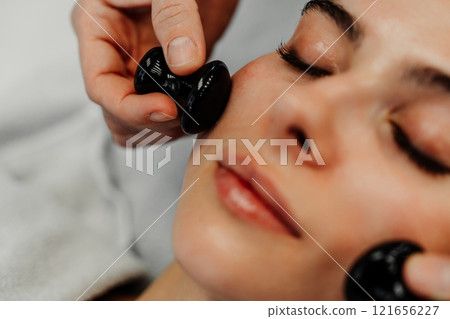 Woman receiving facial treatment with tools at a wellness spa during daytime 121656227