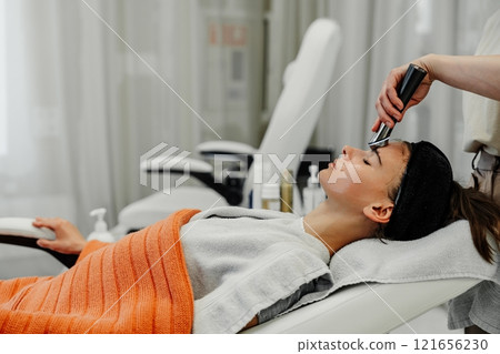 Young woman enjoys facial treatment at spa during relaxing afternoon appointment 121656230