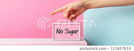 Promoting a sugar free lifestyle, a woman's hand points to a lightbox with no sugar against a pink and blue backdrop, highlighting the importance of reducing sugar for health 121657618
